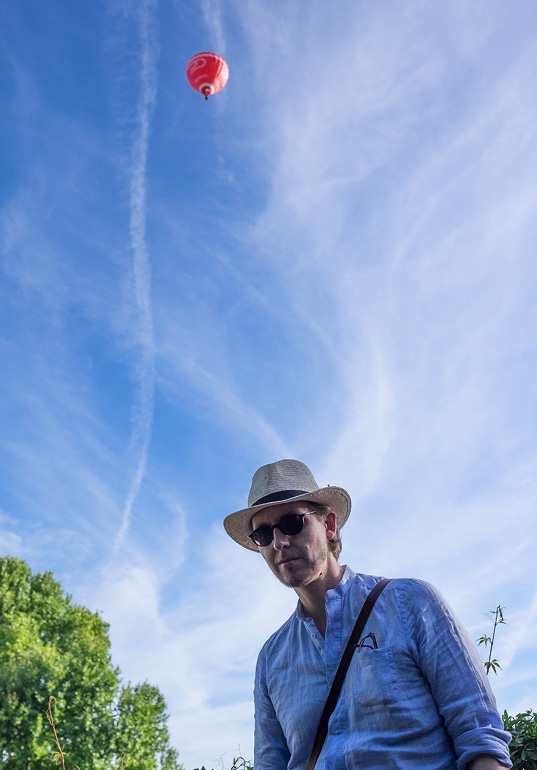 Jens Schellhase mit Strohut, ein roter Ballon im Hintergrund